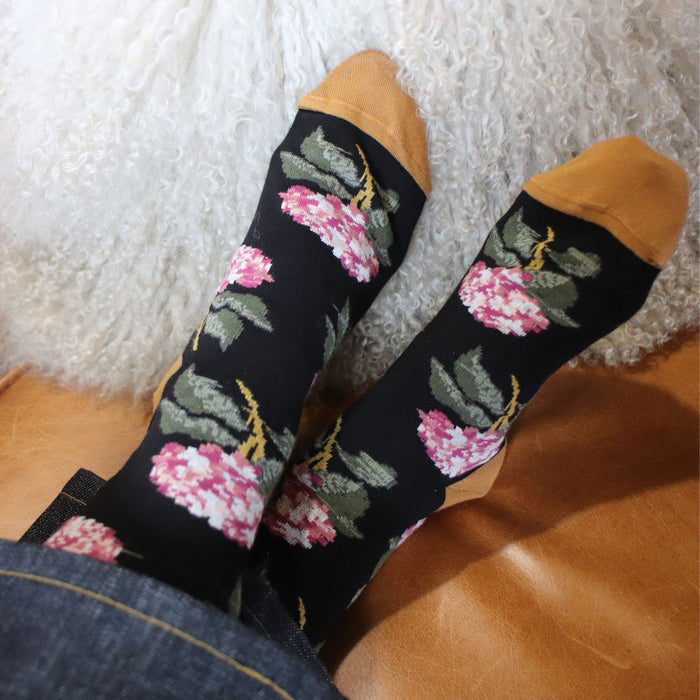 woman wearing floral cotton socks on a leather sofa 